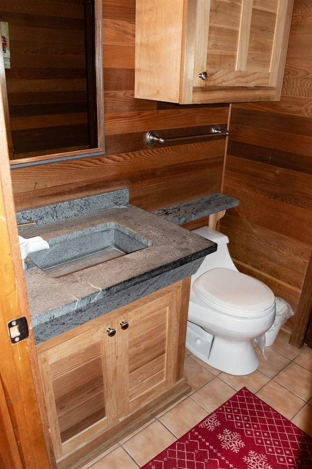 bathroom featuring toilet, vanity, wooden walls, and tile patterned flooring