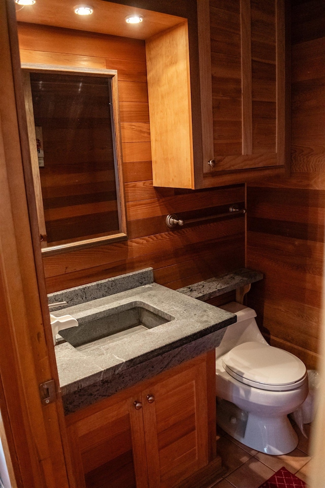 bathroom featuring vanity, tile patterned floors, toilet, and wood walls