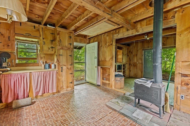 miscellaneous room with wood ceiling, wood walls, and a wood stove