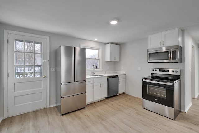 kitchen with white cabinetry, sink, light hardwood / wood-style floors, and appliances with stainless steel finishes