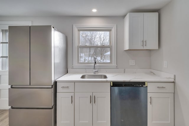 kitchen featuring sink, stainless steel appliances, light stone countertops, light hardwood / wood-style floors, and white cabinets