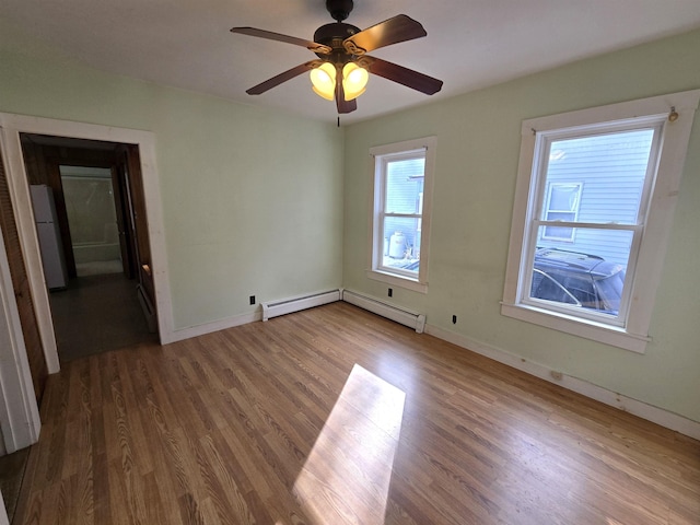 unfurnished room with hardwood / wood-style flooring, a baseboard heating unit, and ceiling fan