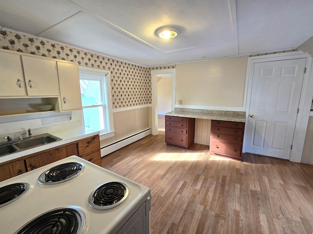 kitchen with electric stove, sink, a baseboard radiator, cream cabinetry, and light wood-type flooring