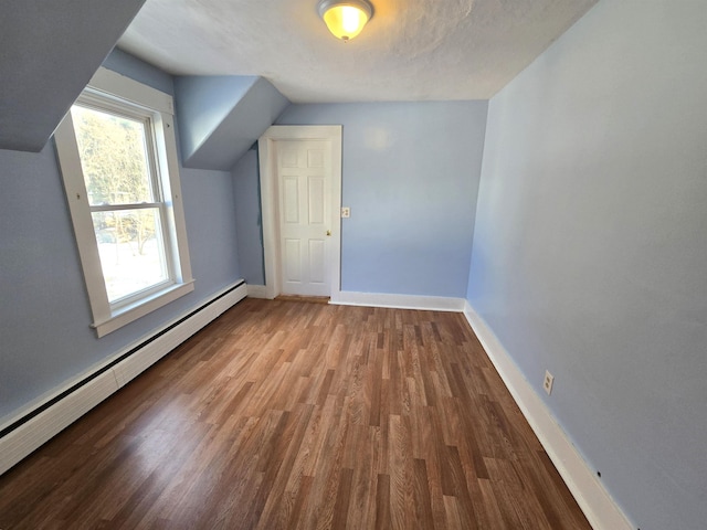 additional living space with hardwood / wood-style flooring, lofted ceiling, and baseboard heating