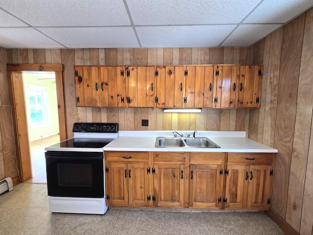 kitchen featuring range with electric cooktop, sink, a drop ceiling, and wood walls