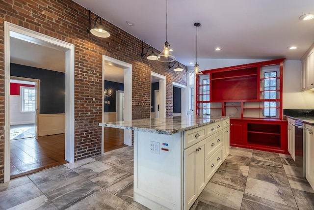 kitchen featuring hanging light fixtures, brick wall, a center island, and dark stone counters