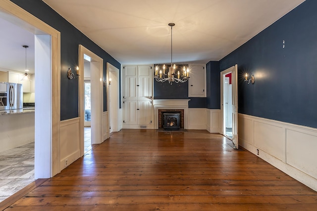 unfurnished living room with an inviting chandelier and dark hardwood / wood-style flooring