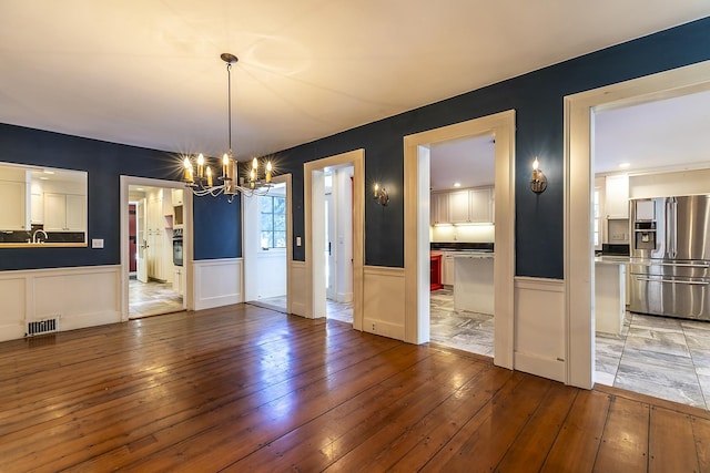 unfurnished dining area with hardwood / wood-style floors and an inviting chandelier