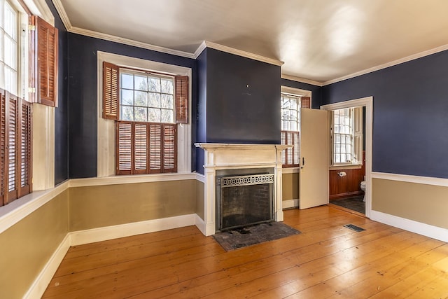 unfurnished living room featuring hardwood / wood-style flooring, ornamental molding, and a healthy amount of sunlight