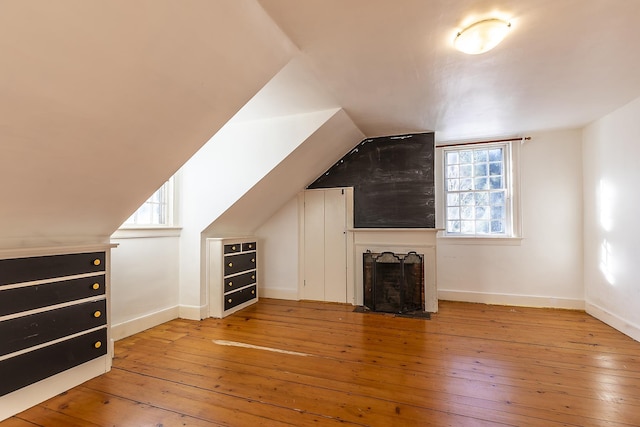 additional living space with vaulted ceiling, a healthy amount of sunlight, and light hardwood / wood-style flooring