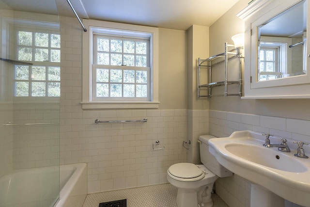 bathroom with tile patterned floors, toilet, sink, and tile walls