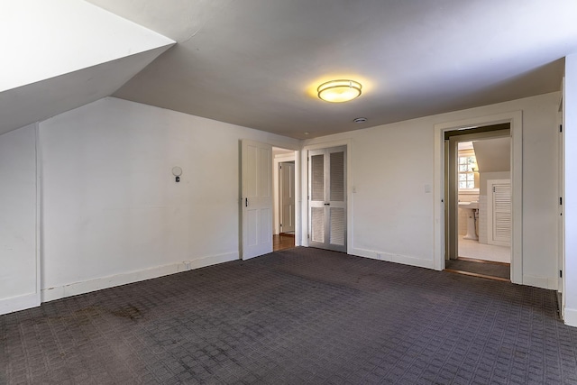 unfurnished bedroom featuring vaulted ceiling and dark carpet