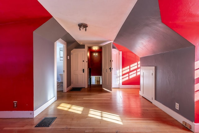 additional living space with lofted ceiling and light hardwood / wood-style flooring