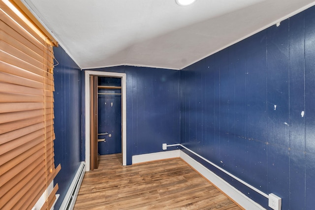 interior space with hardwood / wood-style flooring, lofted ceiling, a baseboard heating unit, and wood walls