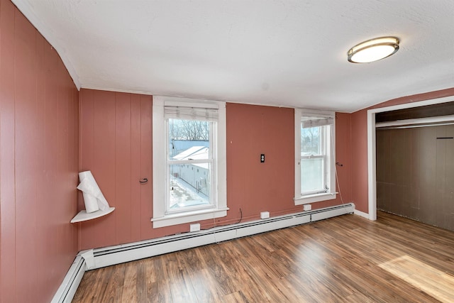 interior space with vaulted ceiling, a baseboard heating unit, light hardwood / wood-style flooring, and a closet