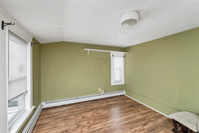 empty room featuring baseboard heating, lofted ceiling, and plenty of natural light