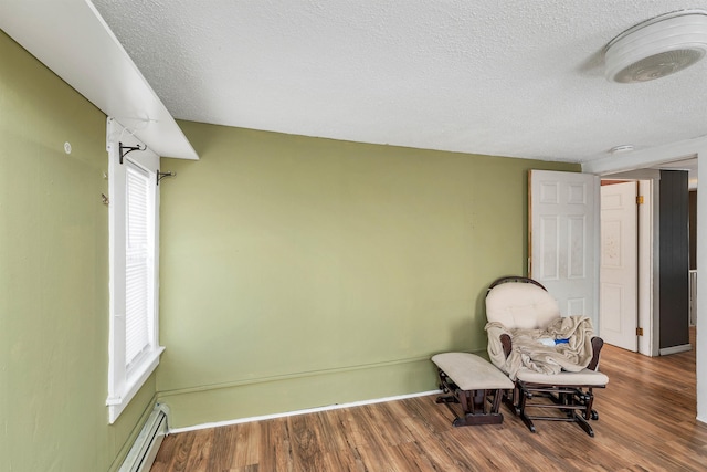 unfurnished room featuring a baseboard radiator, hardwood / wood-style floors, and a textured ceiling