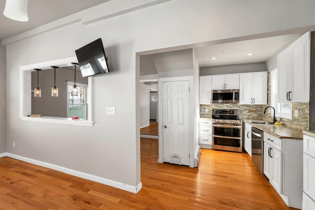 kitchen featuring white cabinetry, light hardwood / wood-style flooring, stainless steel appliances, and tasteful backsplash