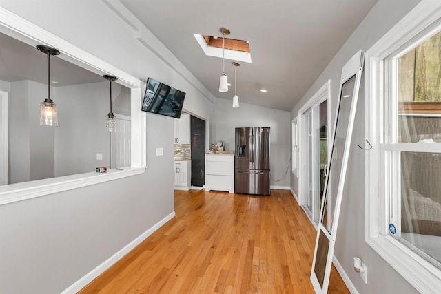 corridor featuring vaulted ceiling with skylight and light wood-type flooring