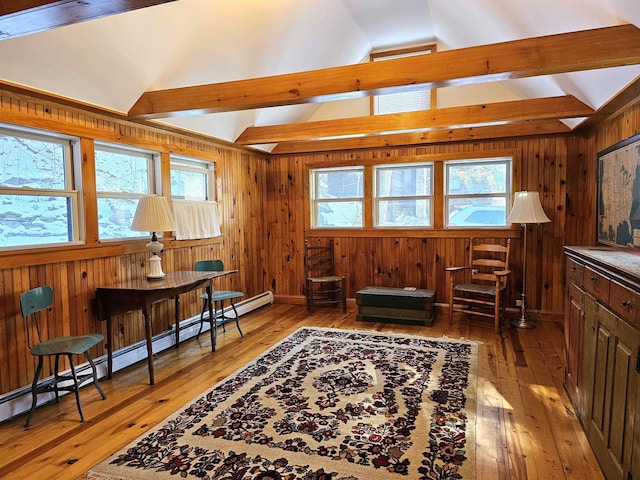 living area featuring a healthy amount of sunlight, light wood-type flooring, and vaulted ceiling with beams