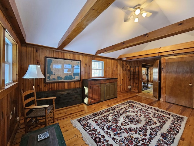 living area with wood-type flooring, beamed ceiling, and wood walls