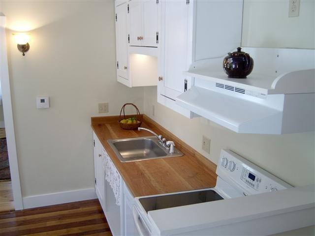 kitchen with white cabinets, dark hardwood / wood-style floors, sink, and electric range