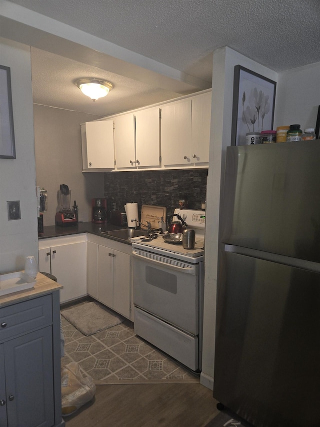 kitchen with stainless steel refrigerator, sink, white cabinets, decorative backsplash, and white electric range oven