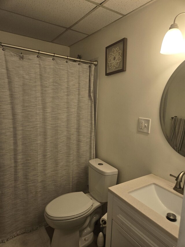 bathroom with a shower with curtain, vanity, a paneled ceiling, and toilet