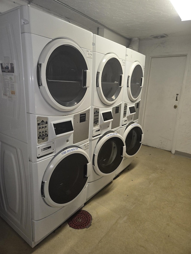 clothes washing area featuring washing machine and dryer, a textured ceiling, and stacked washer / dryer