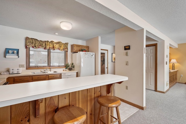 kitchen featuring sink, a kitchen breakfast bar, light colored carpet, kitchen peninsula, and white appliances