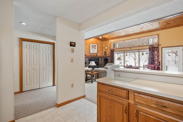 kitchen with wooden walls, a brick fireplace, and light carpet