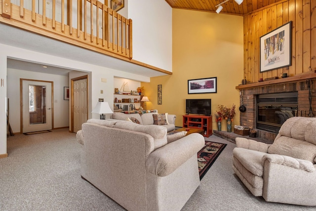 carpeted living room with wood ceiling, wooden walls, a brick fireplace, and a high ceiling