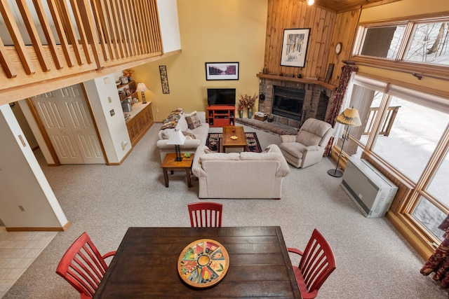 carpeted living room with a brick fireplace, a towering ceiling, and wood walls