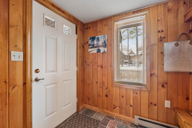 doorway to outside featuring a baseboard radiator, a textured ceiling, and wood walls