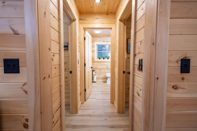 hall featuring light hardwood / wood-style flooring, wood ceiling, and wood walls