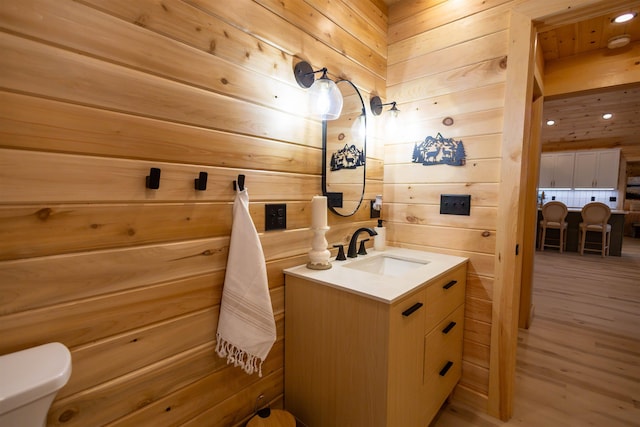 bathroom featuring wooden walls, vanity, and toilet