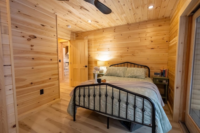 bedroom featuring light hardwood / wood-style flooring, wooden ceiling, ceiling fan, and wood walls