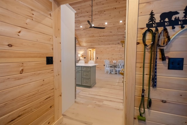 hallway featuring light wood-type flooring, wood ceiling, wooden walls, and vaulted ceiling