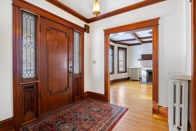 foyer entrance featuring ornamental molding, radiator heating unit, coffered ceiling, and light wood-type flooring