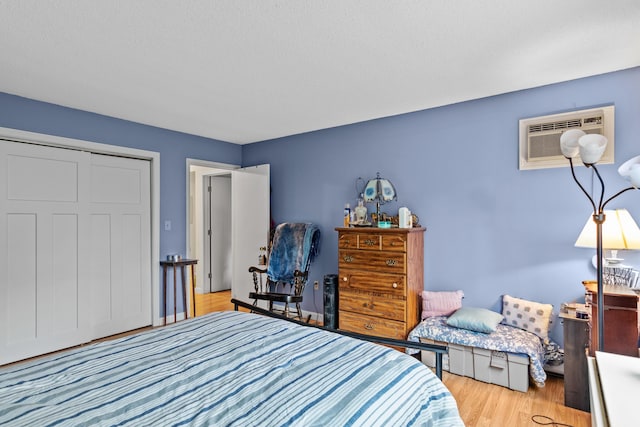 bedroom with a wall mounted air conditioner and light wood-type flooring