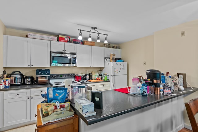 kitchen featuring white cabinetry, kitchen peninsula, white fridge, and electric range oven