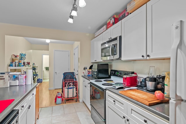 kitchen featuring light tile patterned flooring, dishwasher, white cabinets, white refrigerator, and electric stove