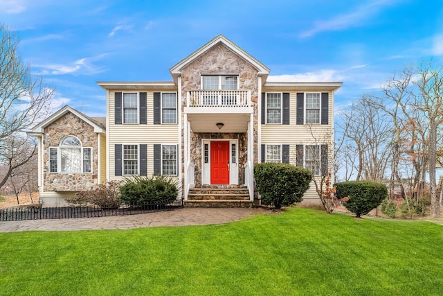 view of front of house featuring a front lawn and a balcony