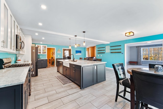 kitchen with a spacious island, sink, white cabinetry, appliances with stainless steel finishes, and pendant lighting