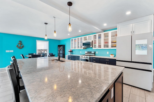 kitchen featuring sink, a breakfast bar, white cabinetry, stainless steel appliances, and a large island with sink