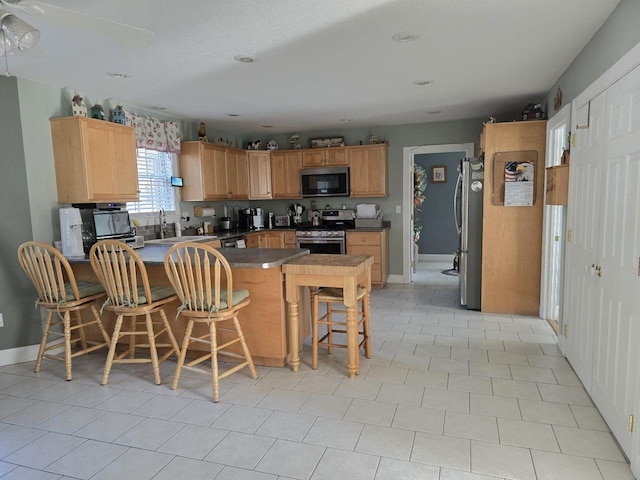 kitchen with stainless steel appliances, sink, a kitchen bar, and kitchen peninsula