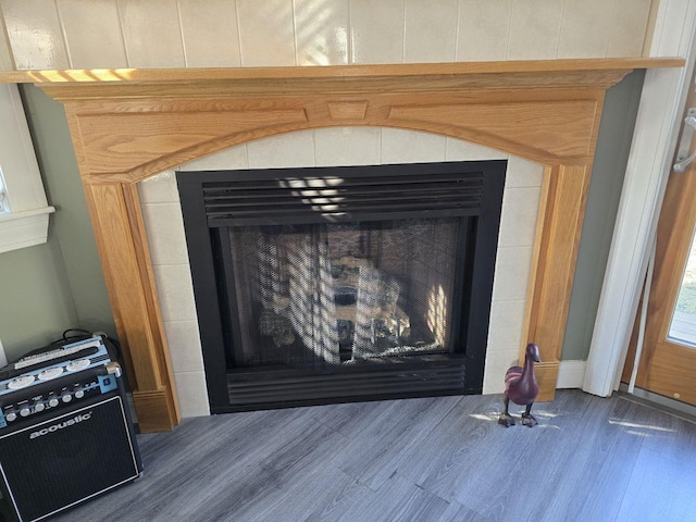 interior details featuring wood-type flooring and a tiled fireplace