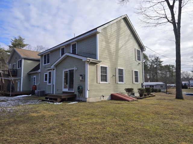 rear view of property featuring a deck, a lawn, and cooling unit