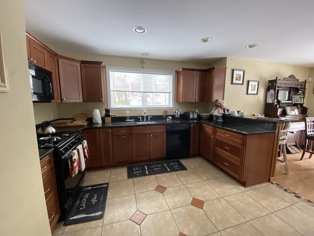 kitchen featuring sink, light tile patterned floors, kitchen peninsula, dark stone counters, and black appliances