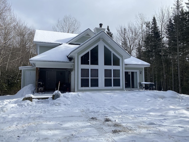 snow covered back of property featuring a chimney